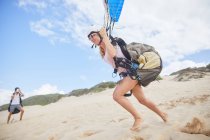 Female paraglider running, taking off on beach — Stock Photo