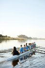 Female rowers rowing scull on sunny lake — Stock Photo
