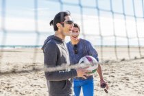 Happy male friends playing beach volleyball on sunny beach — Stock Photo