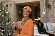 Portrait smiling, confident woman decorating Christmas tree — Stock Photo