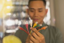 Técnico de TI masculino examinando plugues de conexão multicoloridos — Fotografia de Stock
