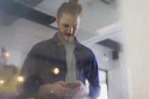 Uomo d'affari sms con smart phone in ufficio — Foto stock