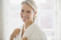 Portrait smiling, confident mature woman in bathrobe — Stock Photo