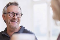 Portrait of mature man laughing at modern home — Stock Photo