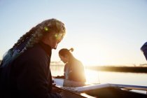 Rameurs femelles préparant l'abattage au lever du soleil au bord du lac — Photo de stock