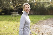 Retrato de mulher loira feliz em camisola cinza no jardim — Fotografia de Stock