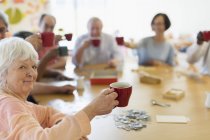 Portrait happy senior woman enjoying afternoon tea with friends in community center — Stock Photo
