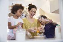 Mother and happy children baking in kitchen — Stock Photo