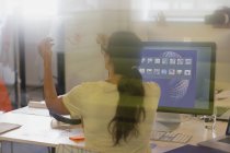 Female designer viewing transparency diagram at computer in office — Stock Photo
