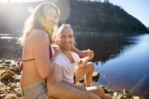 Портретна, безтурботна пара тримає руки на сонячному літньому озері — стокове фото