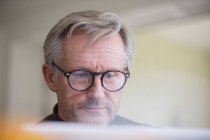 Focalizzato uomo maturo in occhiali da vista che lavorano al computer portatile — Foto stock