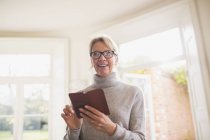 Smiling mature woman using smart phone at home — Stock Photo