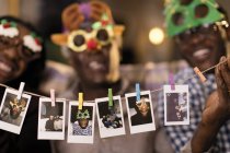 Portrait playful family in Christmas costume goggles showing instant photos — Stock Photo