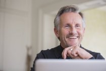 Smiling, confident male freelancer working at laptop — Stock Photo