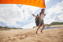 Male paraglider running with parachute on beach — Stock Photo