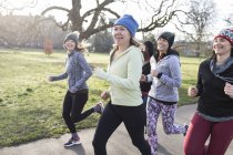 Des coureuses souriantes courent dans un parc ensoleillé — Photo de stock