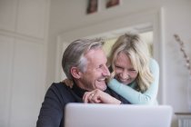 Ridendo, spensierata coppia matura utilizzando il computer portatile — Foto stock