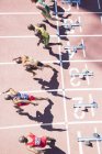 Sprinters taking off from starting blocks on track — Stock Photo