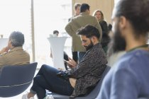 Uomo d'affari sms con smart phone in pubblico conferenza — Foto stock