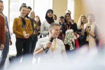 Le public de la conférence applaudit pour sourire haut-parleur féminin avec microphone — Photo de stock