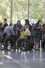 Ділові люди в інвалідних візках говорять у вестибюлі на конференції — стокове фото