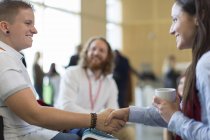 Empresarias estrechando la mano en conferencia en oficina moderna - foto de stock