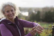 Porträt lächelnd, selbstbewusste, aktive Seniorin, die Sport treibt, Smart Watch checkt — Stockfoto