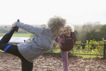 Mulheres idosas ativas amigos alongamento, praticando ioga no parque de outono — Fotografia de Stock