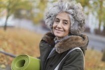 Портрет улыбающейся, уверенной активной пожилой женщины с ковриком для йоги — стоковое фото