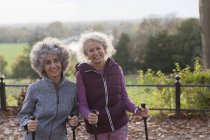 Porträt lächelnde, selbstbewusste aktive Seniorinnen, die mit Stöcken wandern — Stockfoto