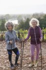 Retrato sonriente, confiado activo senderismo de mujeres mayores amigos con postes en el parque de otoño - foto de stock
