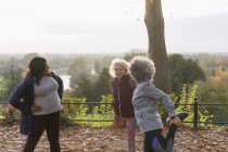 Mujeres mayores activas amigas estirando las piernas, preparándose para correr en el parque de otoño - foto de stock