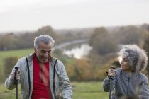 Aktives Seniorenpaar wandert mit Stöcken im Park — Stockfoto