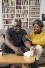 Seniorenpaar überprüft Blutdruck im Wohnzimmer — Stockfoto