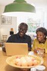 Счастливая пожилая пара с ноутбуком на кухне — стоковое фото