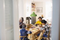 Бабушка и дедушка за обеденным столом с внуками делают уроки — стоковое фото