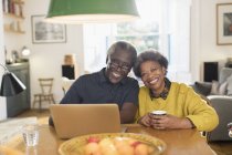 Portrait smiling, confident senior couple using laptop at dining table — Stock Photo