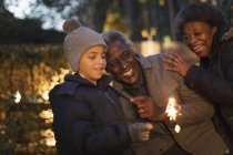 Grandparents and grandson playing with firework sparkler — Stock Photo