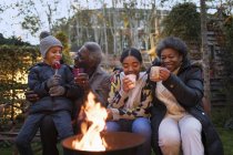 Grandparents and grandchildren drinking hot cocoa at campfire — Stock Photo