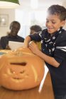 Rapaz sorridente a esculpir abóboras de Halloween — Fotografia de Stock