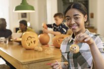 Портрет улыбается, уверенная в себе девочка-подросток держит окрашены Хэллоуин тыквы керамики — стоковое фото