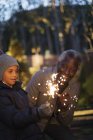 Grandfather and grandson playing with firework sparklers — Stock Photo