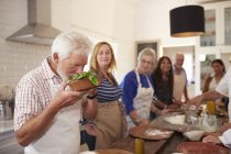 Amici anziani attivi che frequentano corsi di cucina, odorando di basilico fresco — Foto stock