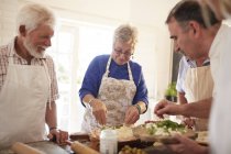 Active senior friends making pizza in cooking class — Stock Photo