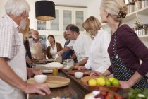 Active senior friends watching chef in pizza cooking class — Stock Photo