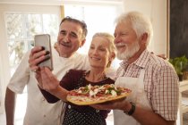 Koch und Seniorenpaar machen Selfie mit Pizza im Kochkurs — Stockfoto