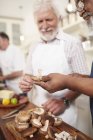 Seniorenfreunde schneiden frische Champignons im Kochkurs — Stockfoto