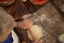 Вид зверху старша жінка котиться, роблячи свіже тісто для піци — стокове фото