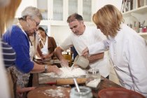 Chef e donna anziana che fanno il nido di farina di pasta per pizza in classe di cucina — Foto stock