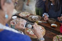 Senior mulher com câmera telefone fotografar pizza caseira em aula de culinária — Fotografia de Stock